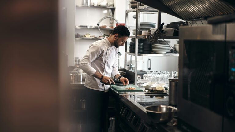 Kucharz krojący warzywa w profesjonalnej kuchni restauracyjnej
